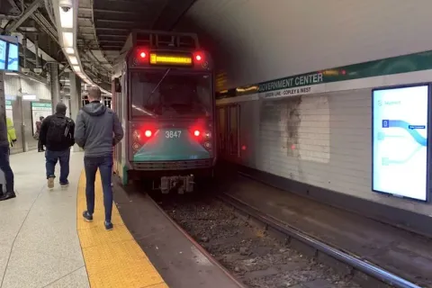 An MBTA Green Line trolley arriving at the platform inside Government Center station in Boston.